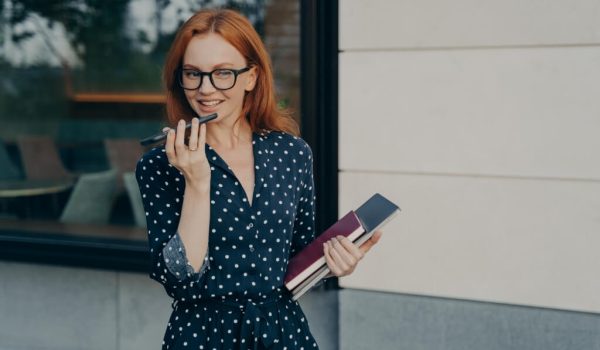 smiling business woman using speakerphone virtual voice assistant mobile phone